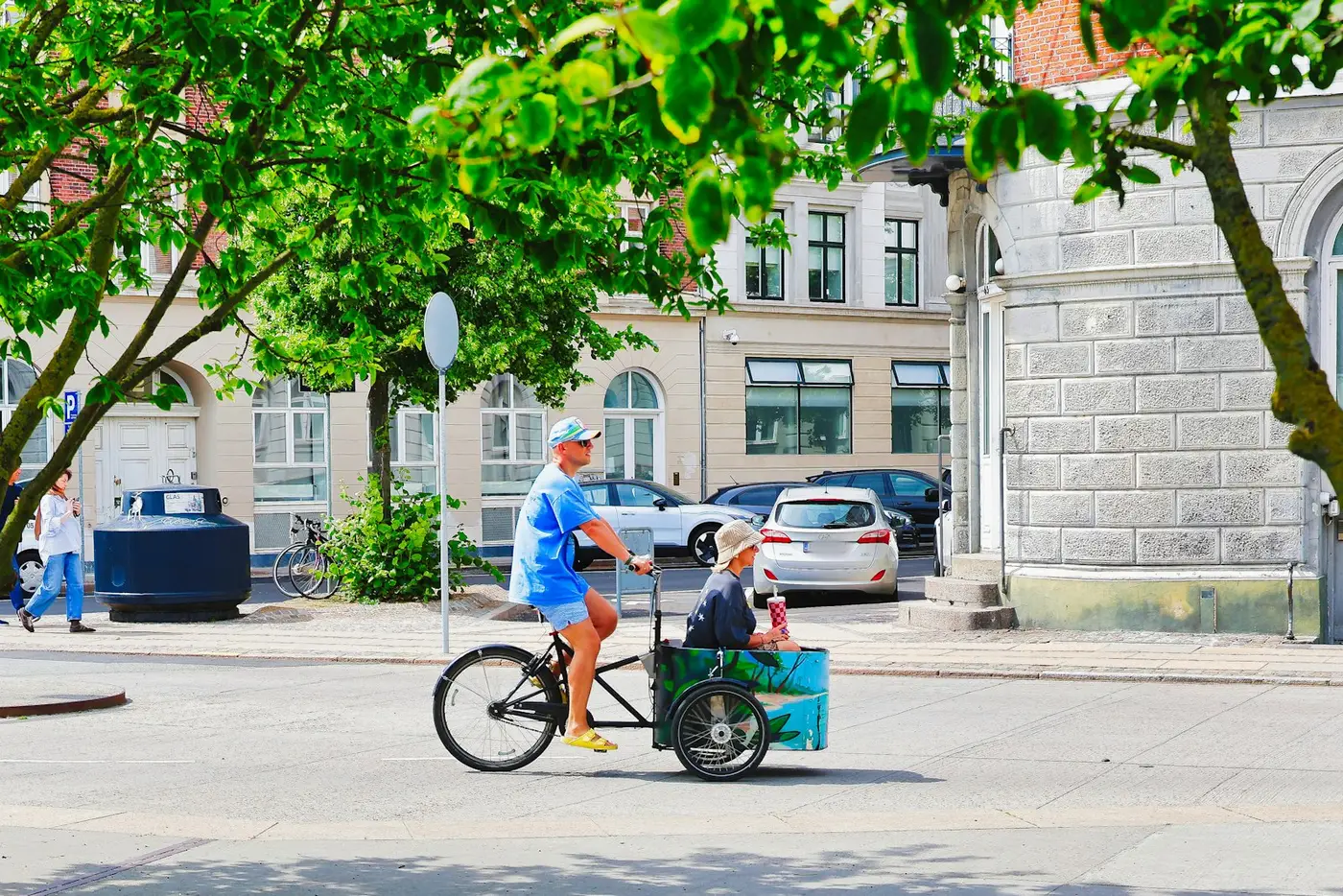 Vater fährt Lastenrad mit Kind in der Kiste, Straßenszene
