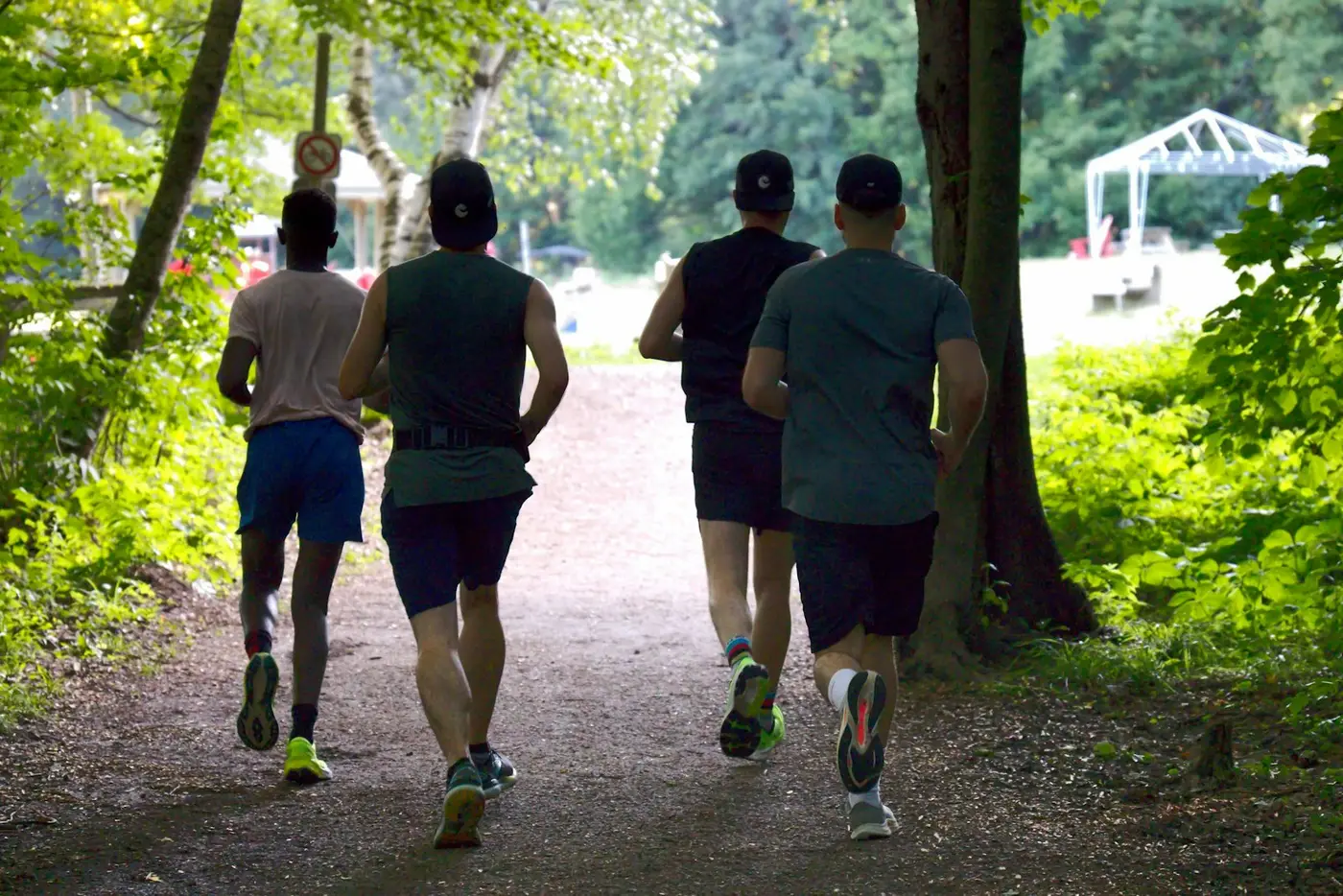 Vier Läufer von hinten auf einem Waldweg im Park
